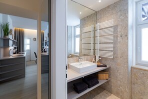 A modern bathroom with a large mirror, a white sink, and a towel rack. - Cozy apartment with a balcony and a view of the garden. (Semmering-Kurort)