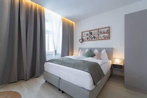 A modern bedroom with a bed, curtains, a wall-mounted photo collage, and a bedside table with a lamp. - Cozy apartment with a balcony and a view of the garden. (Semmering-Kurort)
