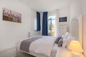 Ein Schlafzimmer mit Bett, Nachttisch, Lampe und Blick ins Freie.