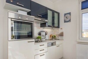 Eine moderne Küche mit eingebauten Geräten, einer Kaffeemaschine und einer Uhr an der Wand.