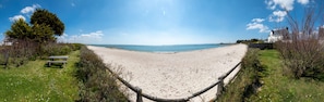 En strand med en träbänk och ett staket.