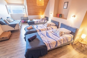 A bedroom with three beds, a wooden ceiling, and a view of the sea. - Large family villa on the beach by Groom* (Larmor-Plage)
