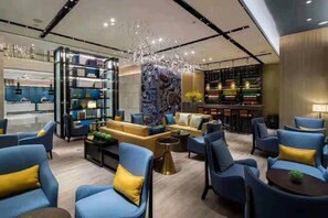 A modern lounge area with sofas, armchairs, and a bar area with shelves. - Echarm Hotel (Heyuan)