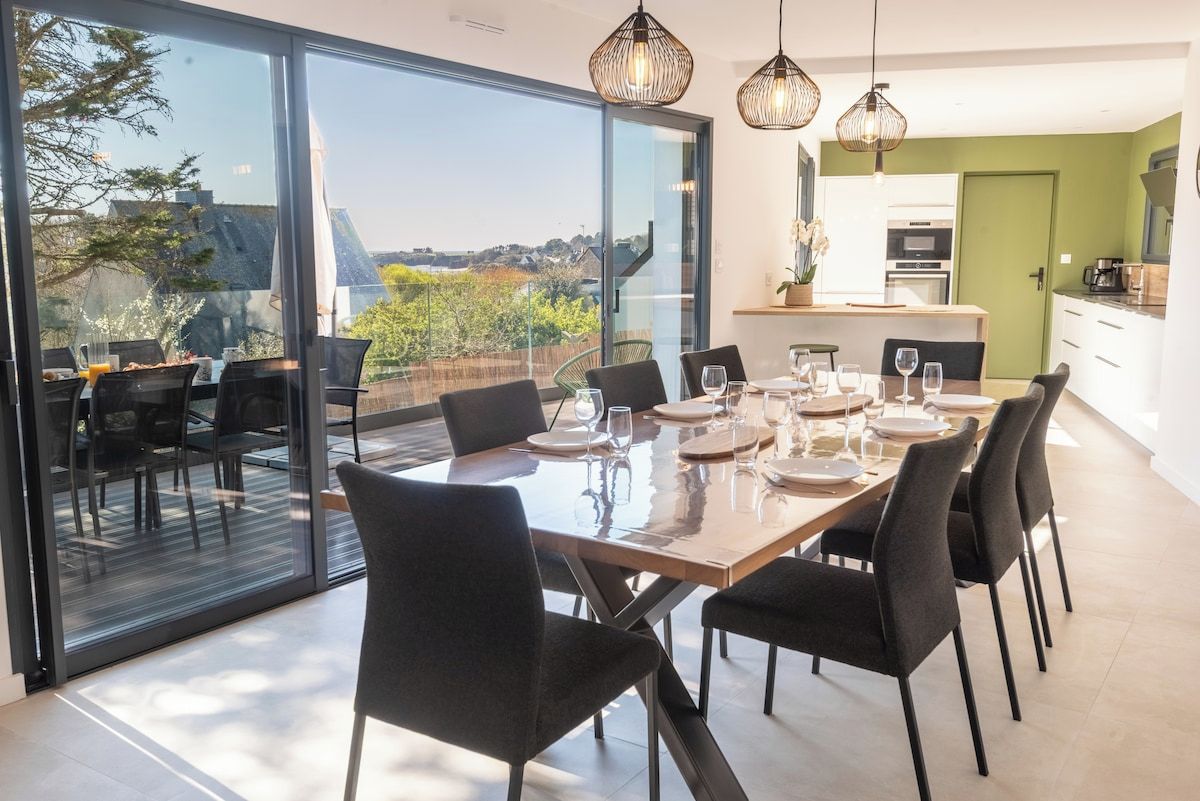 Ein Essbereich mit großem Tisch, Stühlen und Blick durch Glastüren.