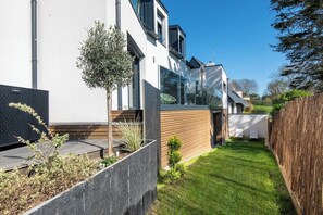 A modern house with a well-maintained lawn and a wooden fence. - Stunning premium family villa, within walking distance of the beach – by Groom* (Guidel)