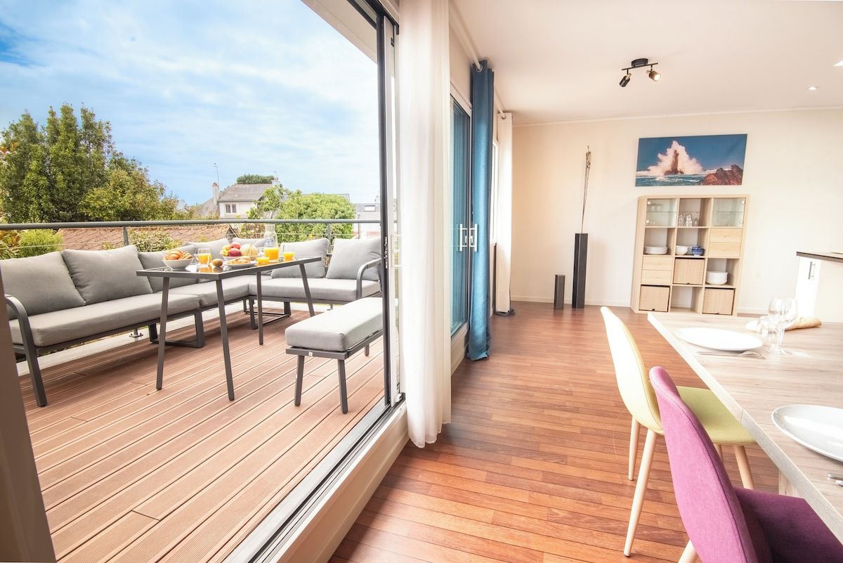 A modern living space with a balcony, a dining area, and a kitchen.