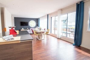 A modern hotel room with a dining area, a large window, and a television. - Modern beachfront house by Groom* (Larmor-Plage)