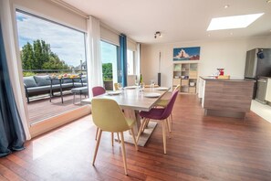 A modern kitchen with a dining area, a sofa, and a view of the outdoors. - Modern beachfront house by Groom* (Larmor-Plage)