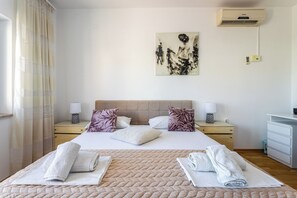 Een hotelkamer met een bed, twee nachtkastjes, een schilderij, een airconditioning en een bureau.