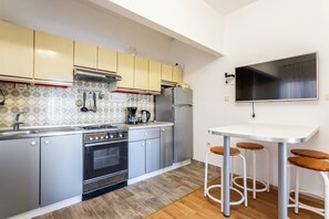 Een moderne keuken met roestvrijstalen apparatuur, houten krukken en een flatscreen televisie.