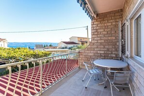 Ein Balkon mit rotem Boden, Metallgeländer und einem Tisch mit Stühlen.