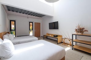 A modern hotel room with two beds, a flat-screen TV, a wooden bench, and a small table. - Mayan Monkey Los Cabos (Cabo San Lucas)