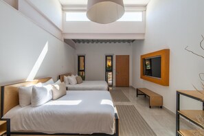 A hotel room with two beds, a TV mounted on the wall, and a skylight. - Mayan Monkey Los Cabos (Cabo San Lucas)