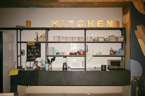 Un área de cocina con un letrero que dice 'KITCHEN' y estantes con diversos utensilios de cocina.