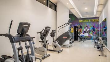 A gym with various exercise equipment, a wall mural, and a ceiling with recessed lighting.