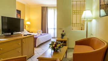 A hotel room with a bed, a TV, a desk, a chair, and a lamp.