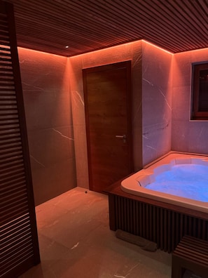 Un cuarto de spa con hidromasaje, paredes de listones de madera y una puerta.