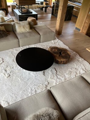 Ein modernes Wohnzimmer mit einer Eckcouch, einem runden schwarzen Couchtisch und einem Holz-Akzentstück.