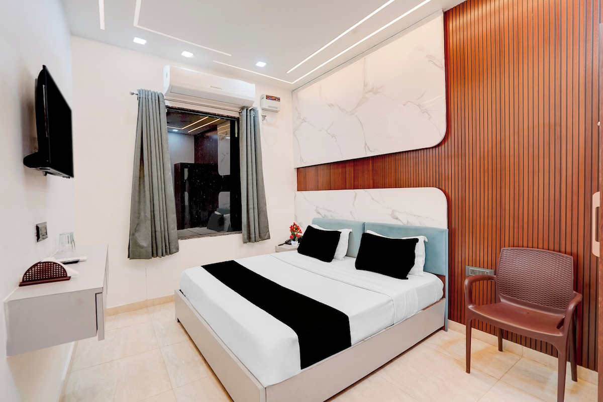 Habitació d'hotel moderna amb llit, escriptori, cadira i televisió.