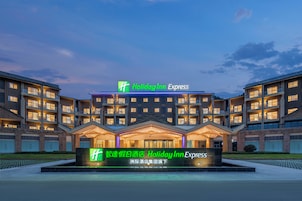 Um hotel Holiday Inn Express com design arquitetônico moderno, apresentando várias varandas e uma entrada bem iluminada.