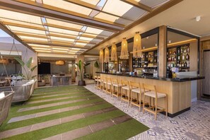 A bar area with a long counter, multiple hanging light fixtures, and a variety of bottles. - Hotel Maspalomas Villas by Dunas - Adults Only (San Bartolomé de Tirajana)