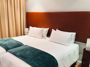 A hotel room with a double bed, two pillows, a bedside table with a lamp, and a wooden headboard. - Cape Town – A Home Like No Other (Cape Town)