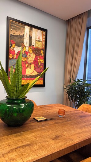 A wooden table with a green vase and a clock, a framed painting on the wall, and a window with curtains. - Cape Town – A Home Like No Other (Cape Town)