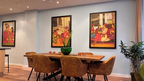 A dining area with a wooden table, four chairs, and three framed paintings on the wall. - Cape Town – A Home Like No Other (Cape Town)