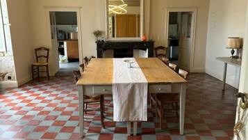 Zona pranzo con pavimento a scacchi, tavolo in legno, sedie e lampada a sospensione moderna.