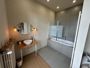 A modern bathroom with a wooden vanity, a white sink, a large mirror, and a bathtub. - les Trois Terrasses (Montpezat-de-Quercy)