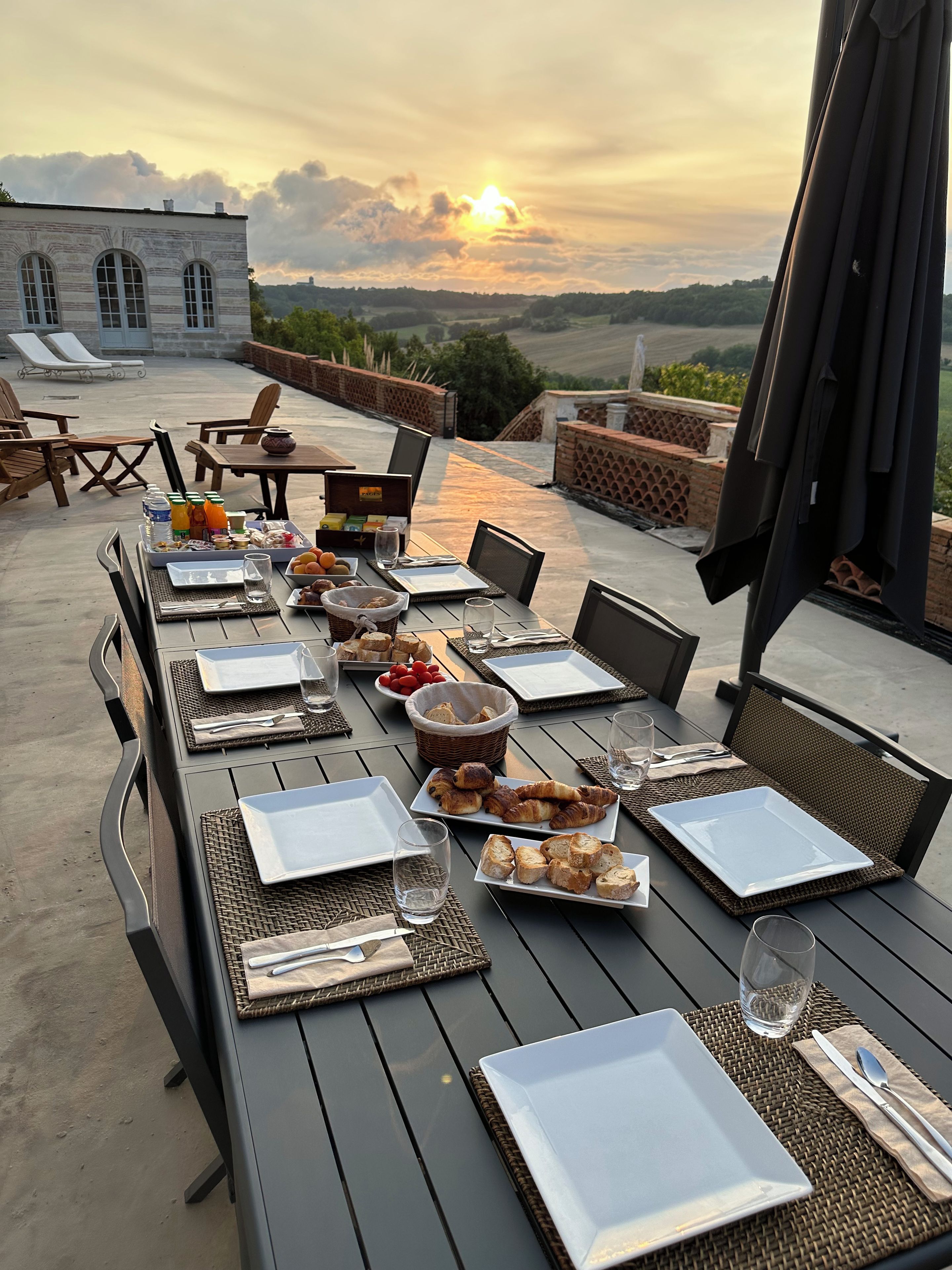 An outdoor dining area with a table set for a meal, overlooking a scenic landscape.