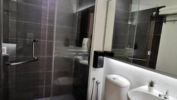 A modern bathroom with a shower, toilet, and sink.