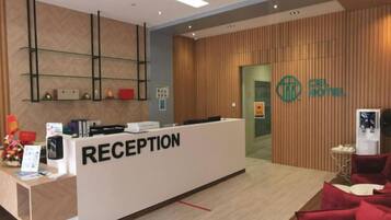 A reception area with a reception desk, a wooden wall, and a logo on the wall.