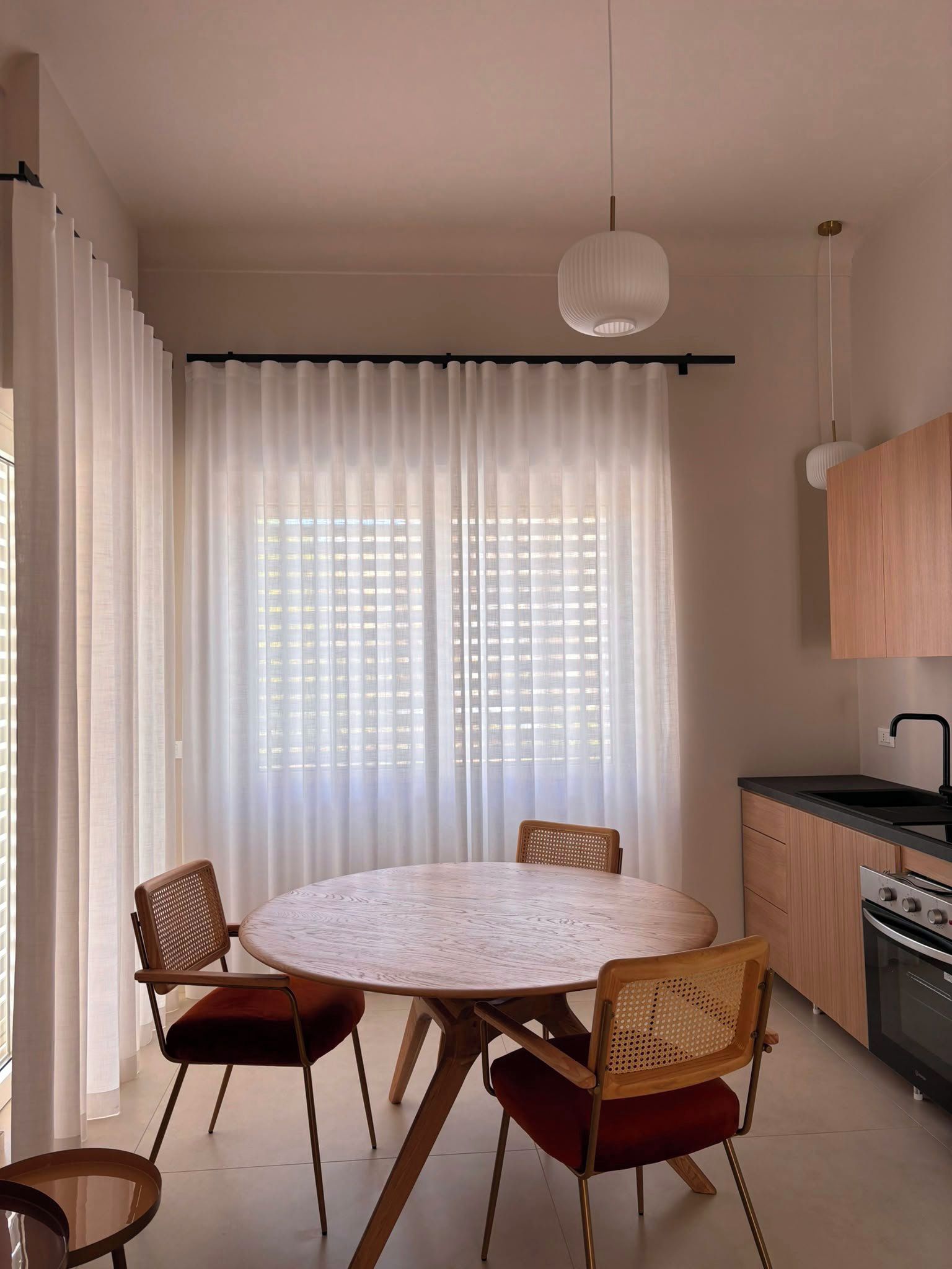 A modern kitchen with a round dining table, chairs, and a pendant light.