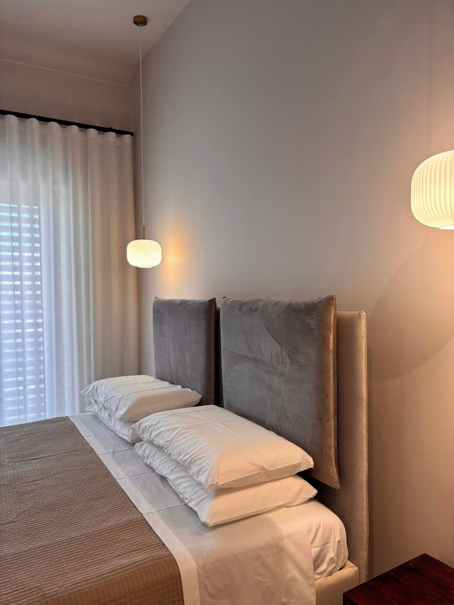 Una habitación de hotel con una cama, cortinas e iluminación en la pared.