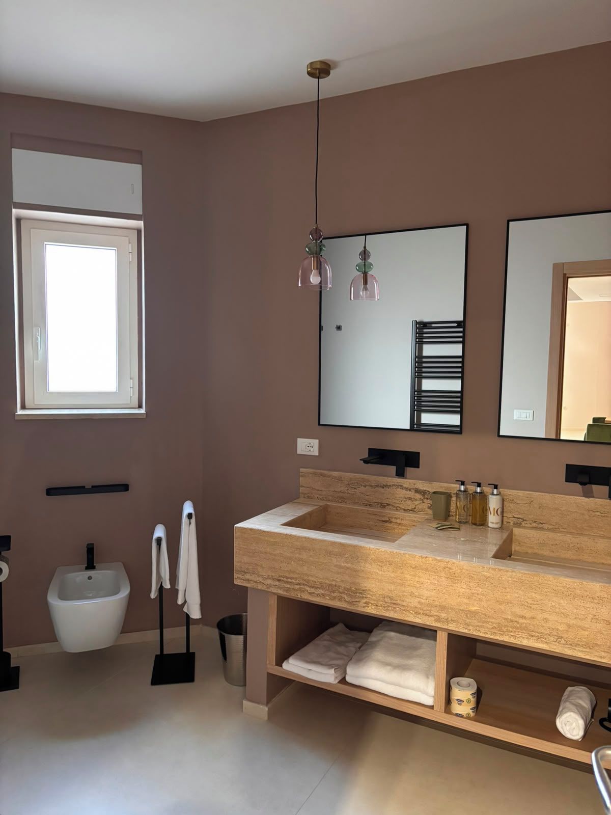 Un baño moderno con un tocador color beige, un bidé y un espejo grande.
