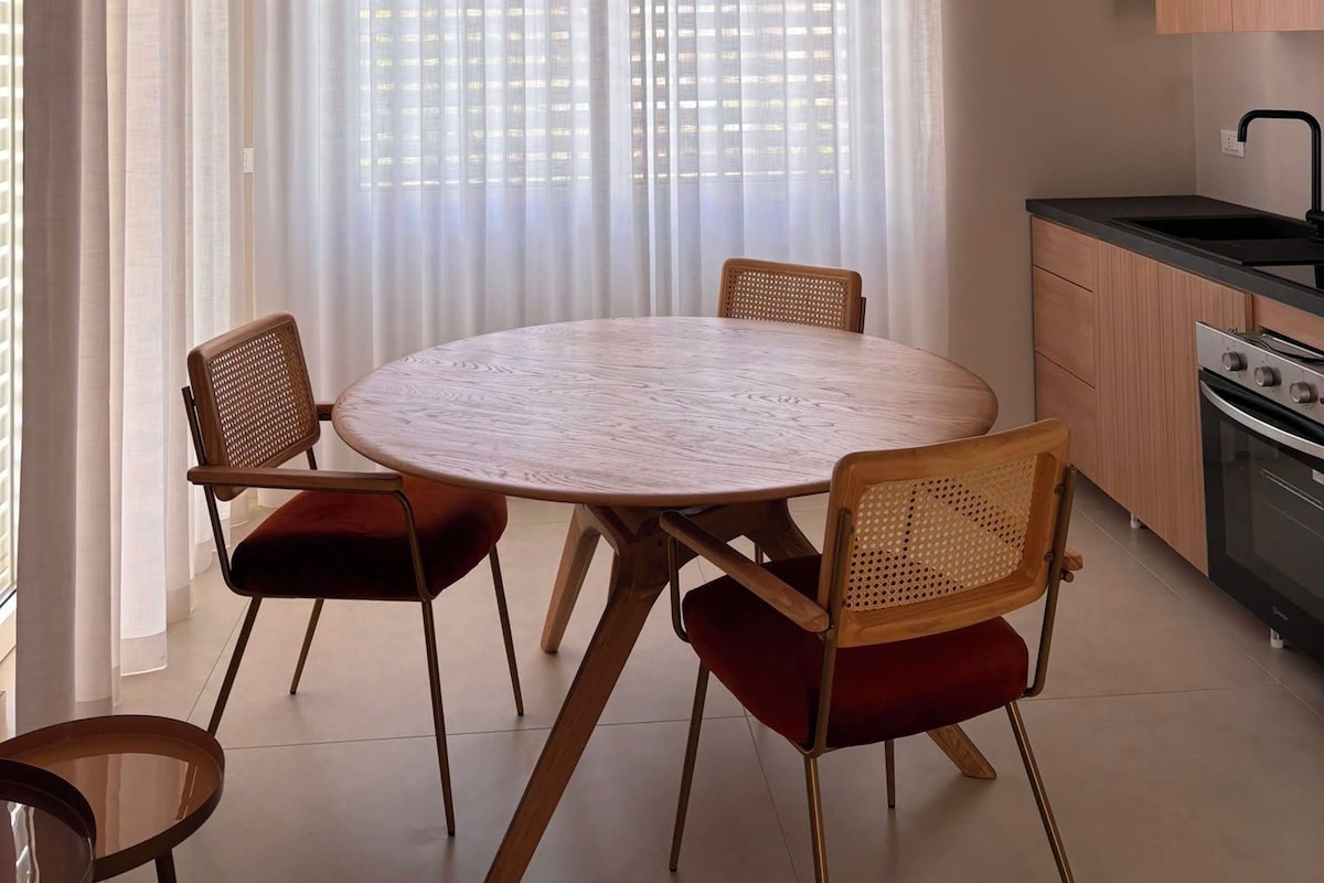 Una cucina moderna con un tavolo rotondo, sedie e una lampada a sospensione.