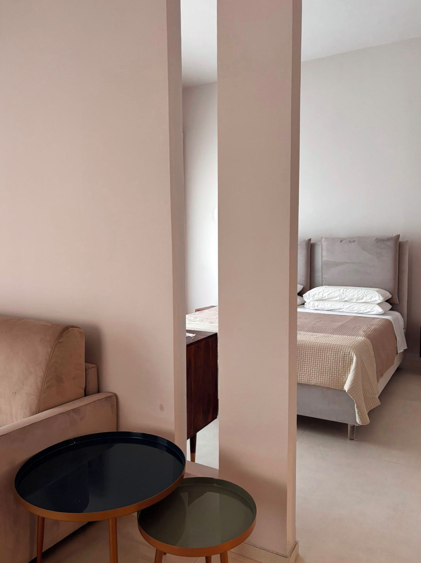 Un dormitorio con una cama, una mesita de noche, una silla y dos pequeñas mesas.