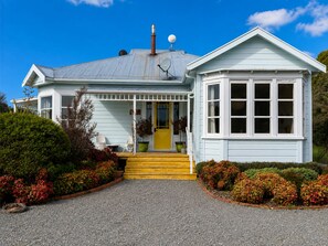 A two-story house with a porch, a chimney, and a satellite dish.
