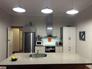 Una cocina con un refrigerador de acero inoxidable, un microondas, un fregadero y un gabinete con un adorno encima.