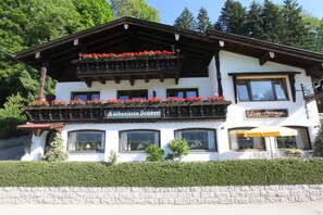 A two-story building with a balcony adorned with red flowers, a sign reading 'Räbersteiner Stüberl,' and a section labeled 'Appartement's.' - Kälbersteinstüberl Vacation Rental (Bischofswiesen)