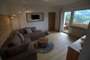Uma sala de estar moderna com um sofá seccional, uma mesa de centro e uma grande janela com vista para o exterior.