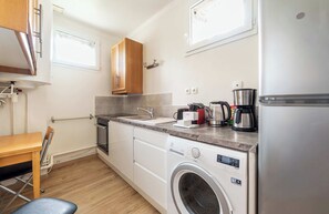 Una cocina compacta equipada con lavadora, cafetera y microondas.