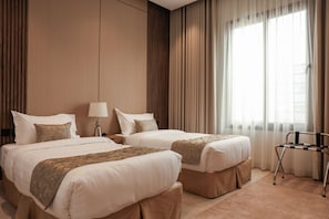 Une chambre d’hôtel avec deux lits, une table de chevet avec une lampe, une chaise et une fenêtre avec des rideaux.
