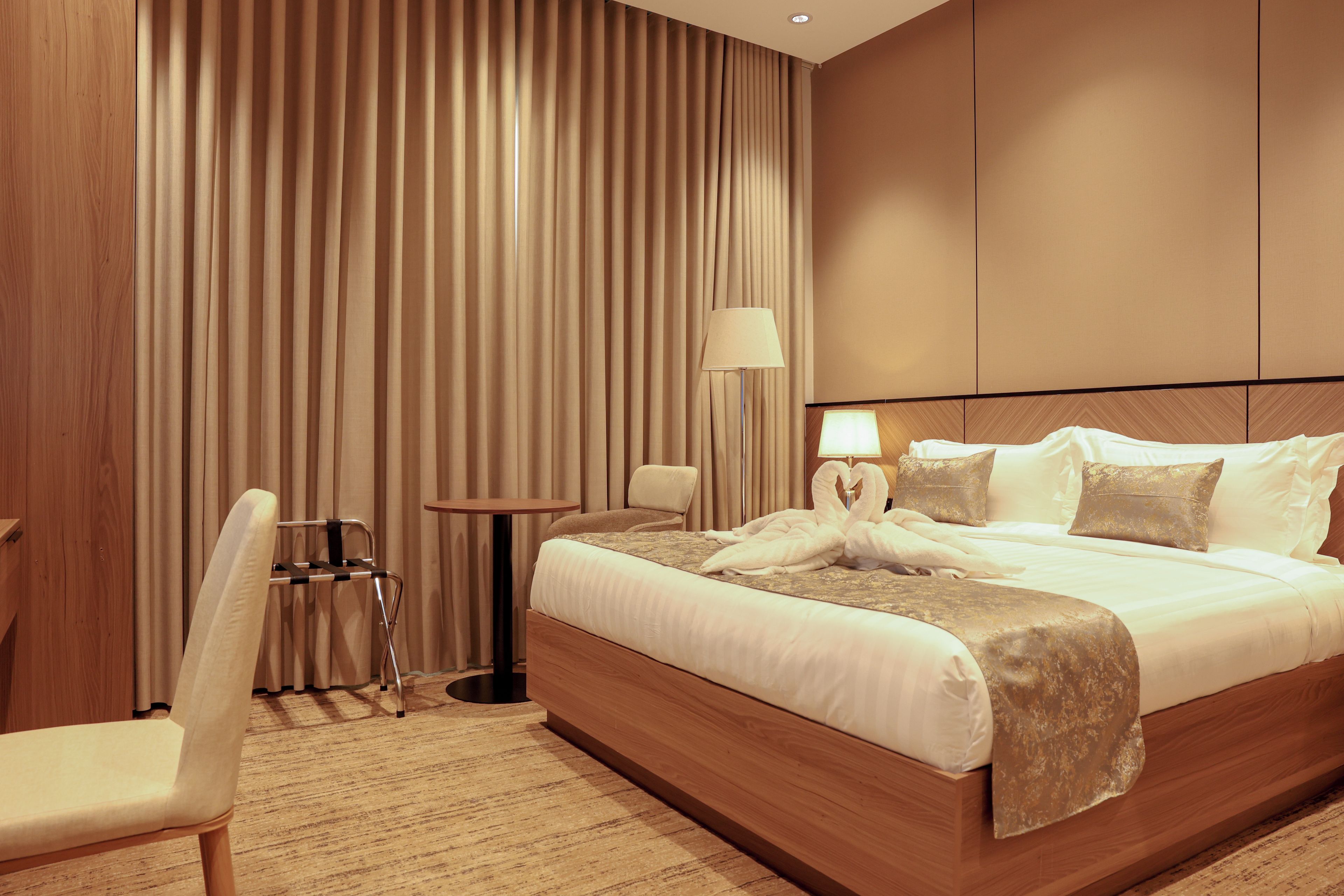 Una habitación de hotel con una cama grande, una silla, una mesita y una lámpara.