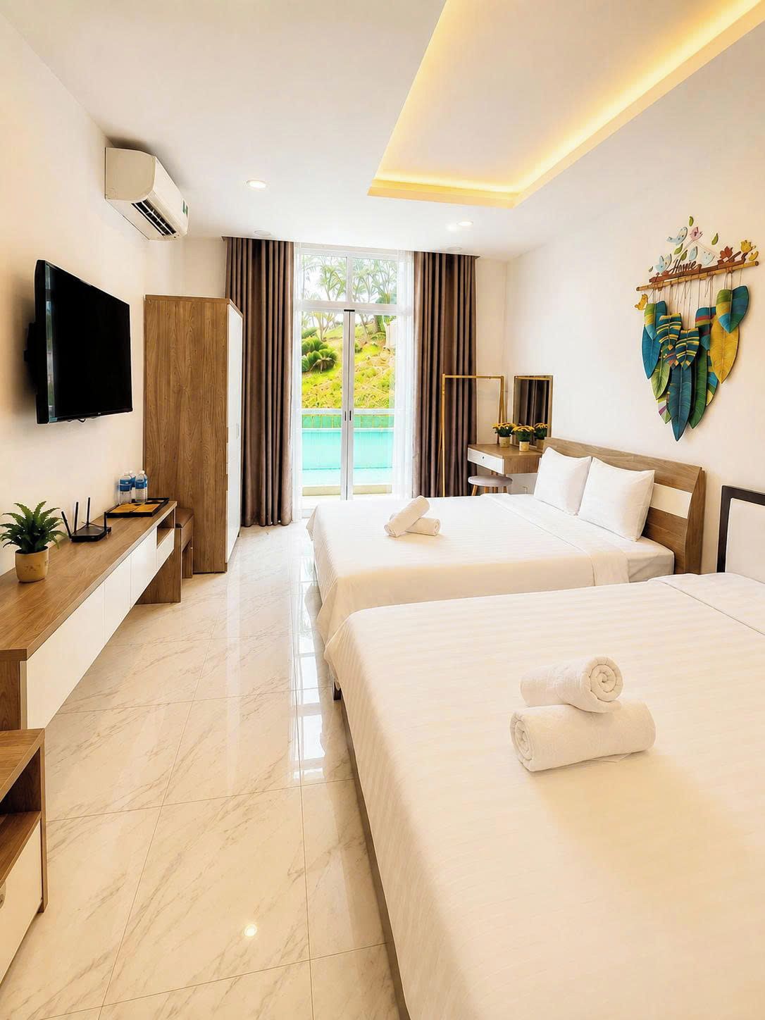 A hotel room with two beds, a flat-screen TV, a desk, and a view of the outdoors.
