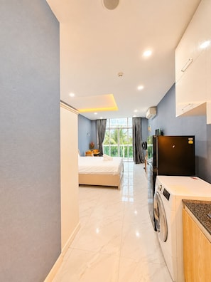 A hotel room with a bed, a washing machine, a TV, and a window with curtains.