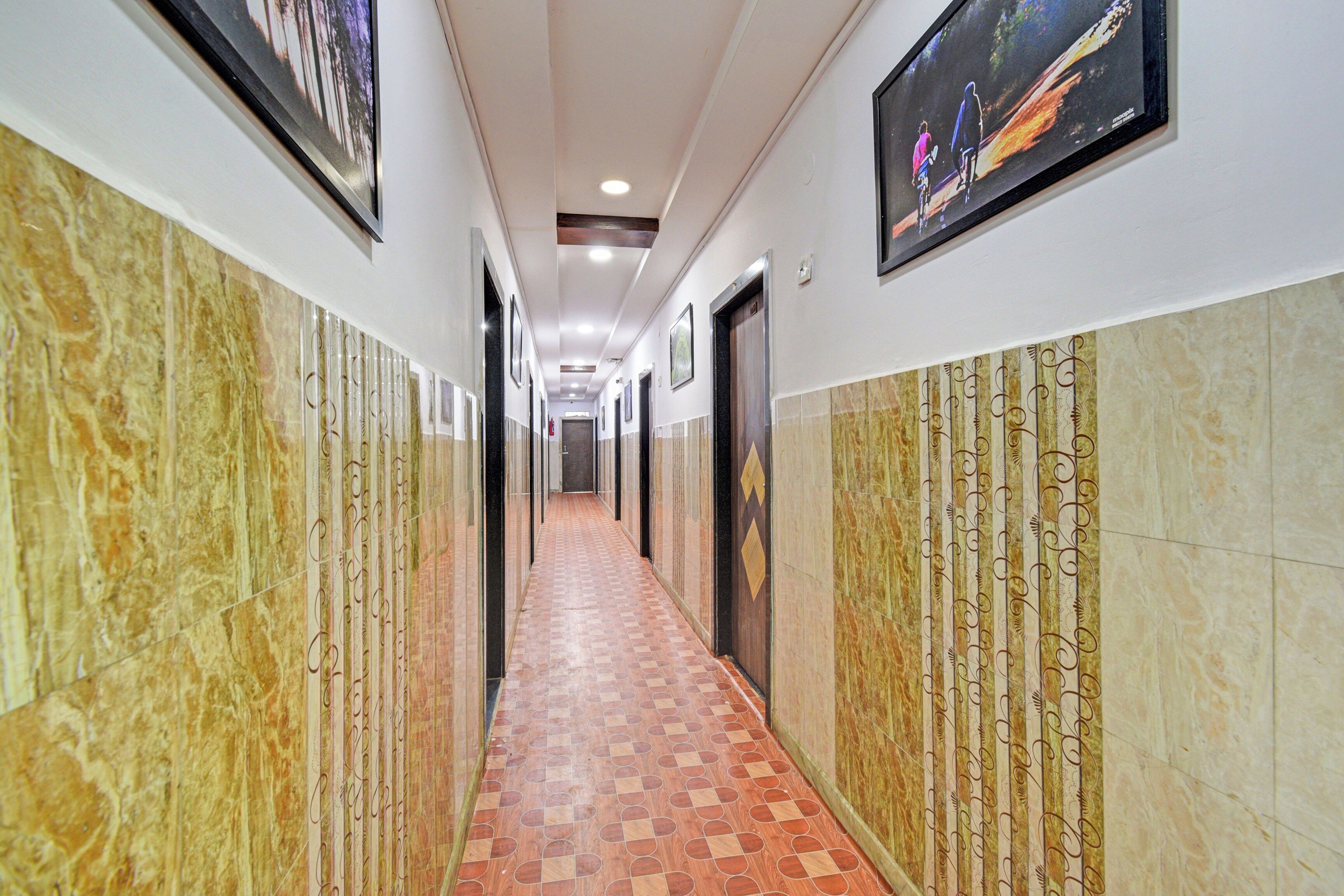A corridor with tiled flooring, framed pictures on the walls, and doors on either side.