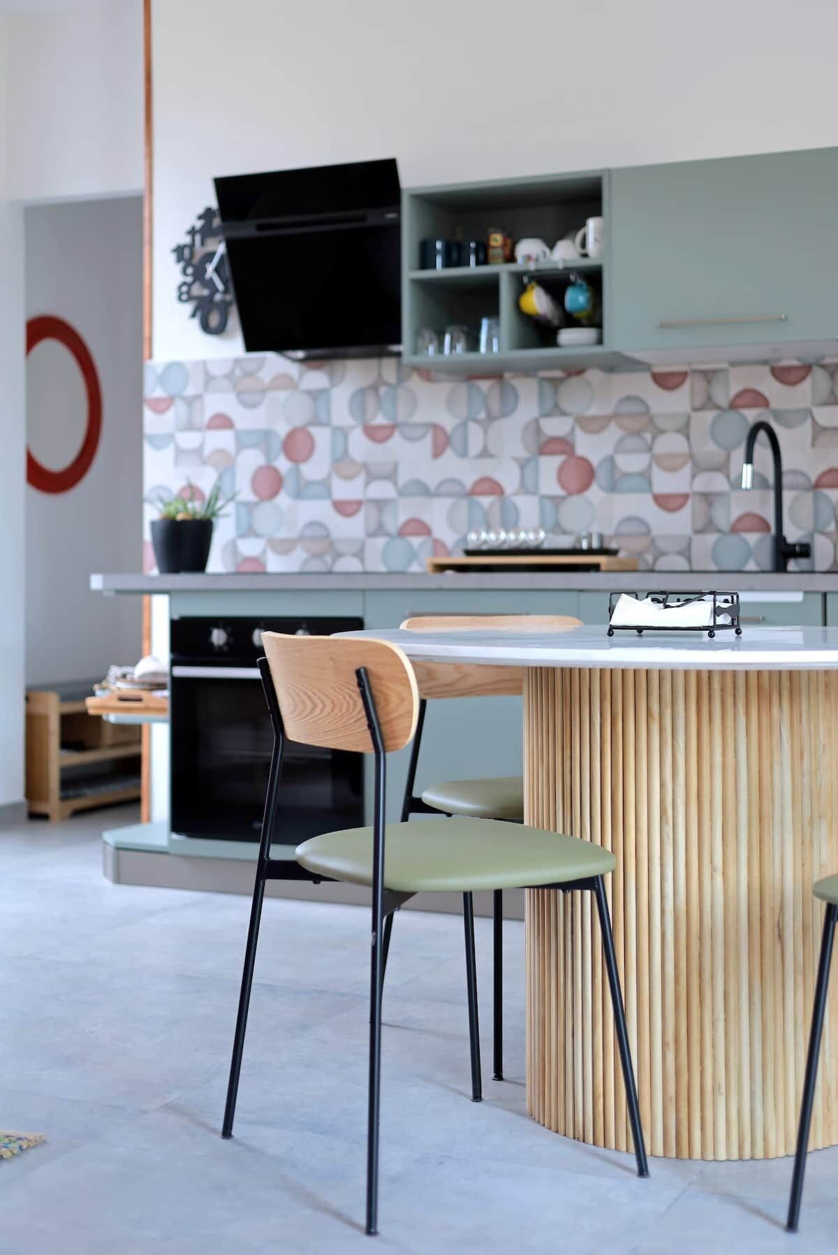 Une cuisine moderne dotée d’un îlot central, d’un four encastré et d’un micro-ondes placé au-dessus du plan de travail.