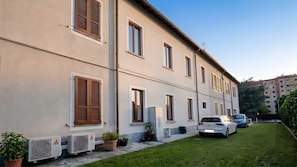 Un edificio su due piani con tetto piatto, diverse finestre e un vialetto lastricato.